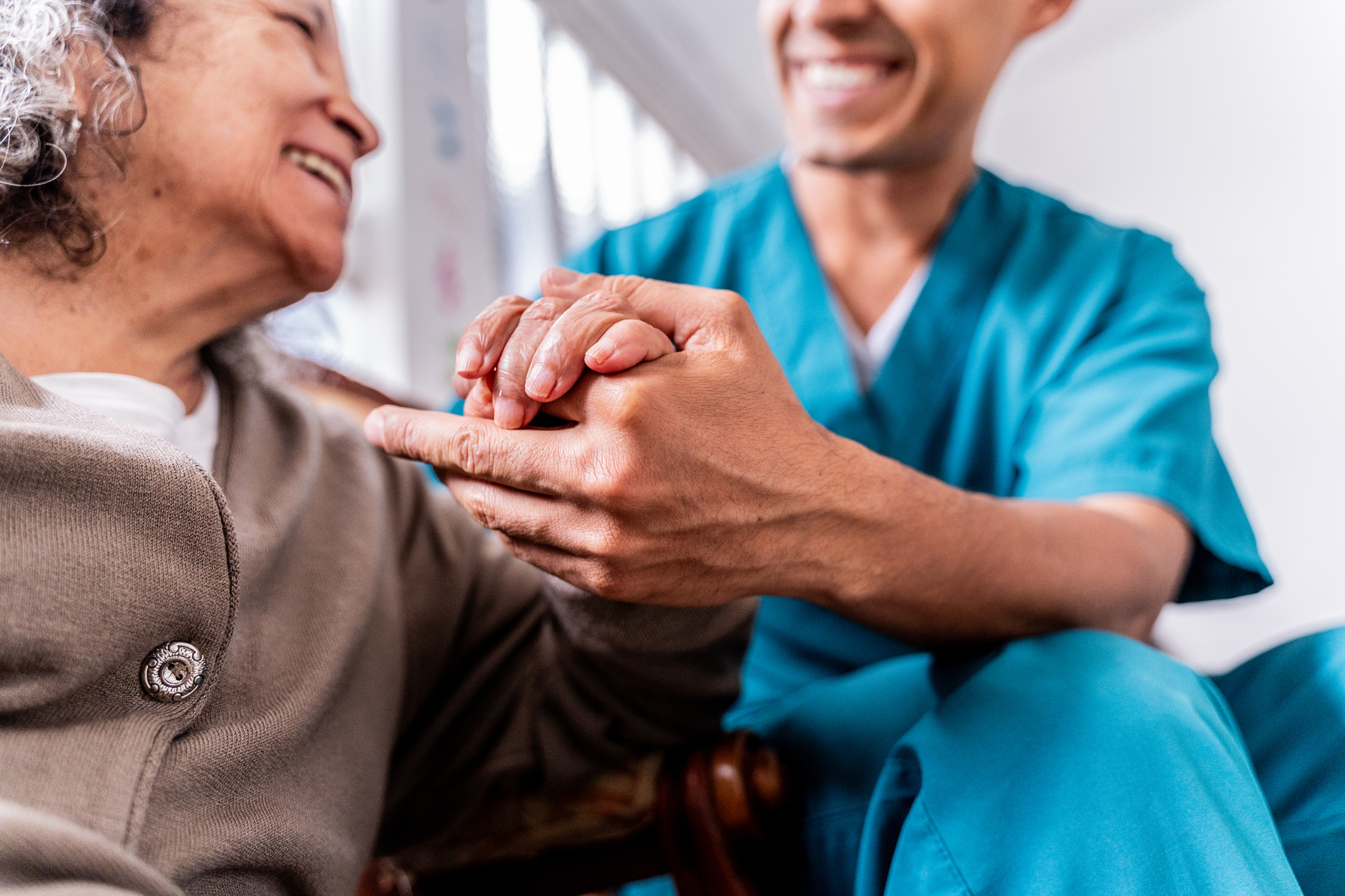 Senior woman holding caregiver’s hands at home Senior woman holding caregiver's hands at home